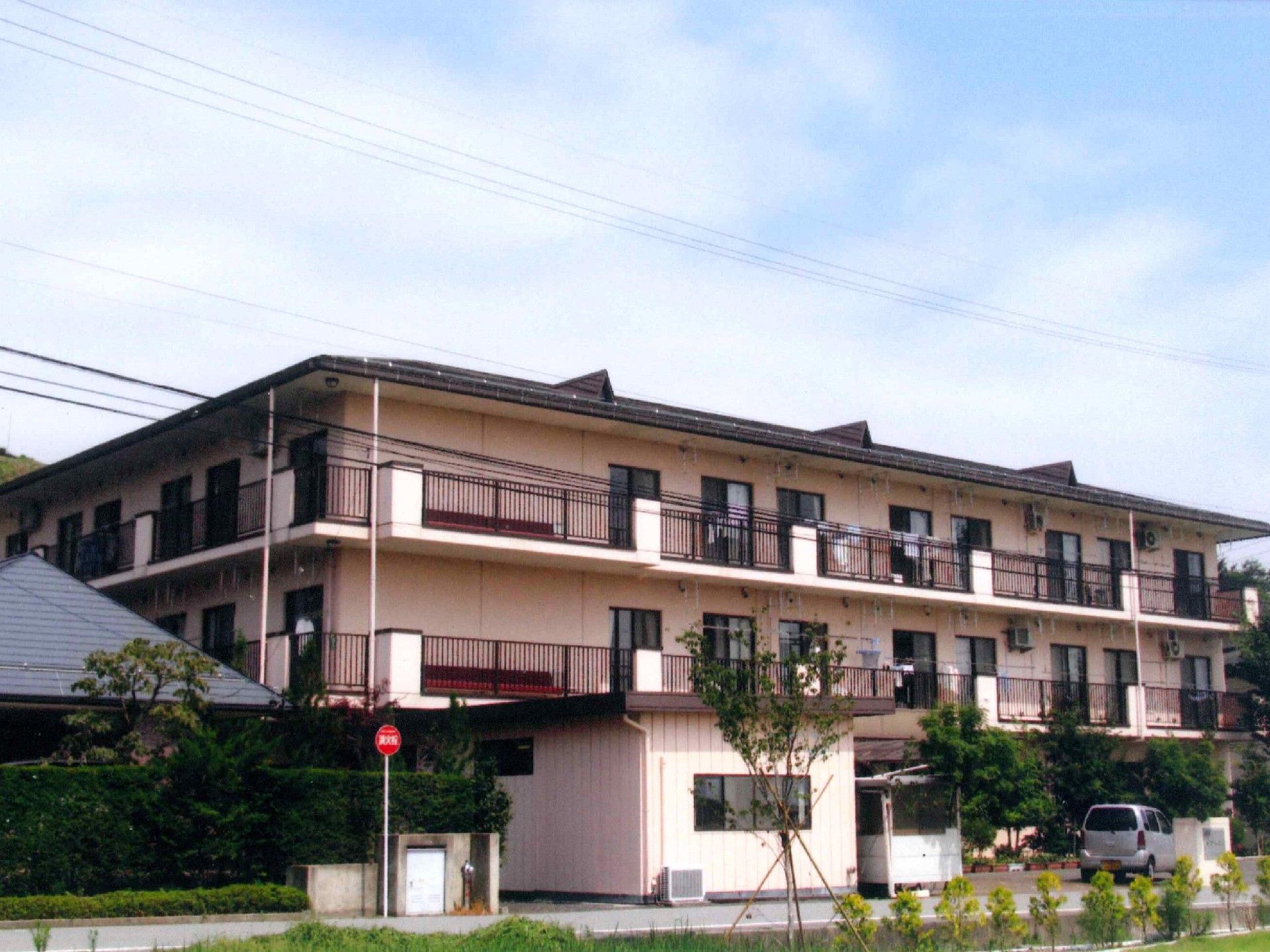 淡い色のやさしい雰囲気の建物。２階と３階部分にはベランダが付いている。