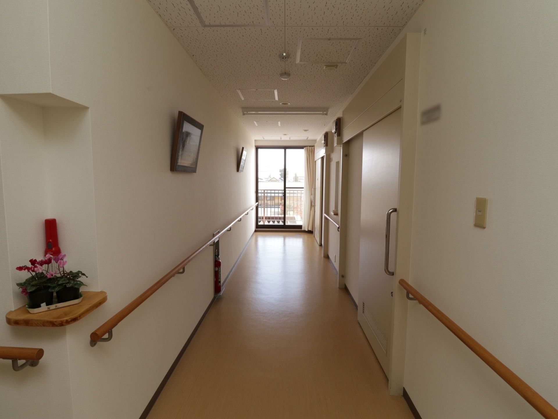 廊下には居室の白い扉が設置されている。大きな取っ手のついたスライド式になっており、安全に開け閉めすることができる。