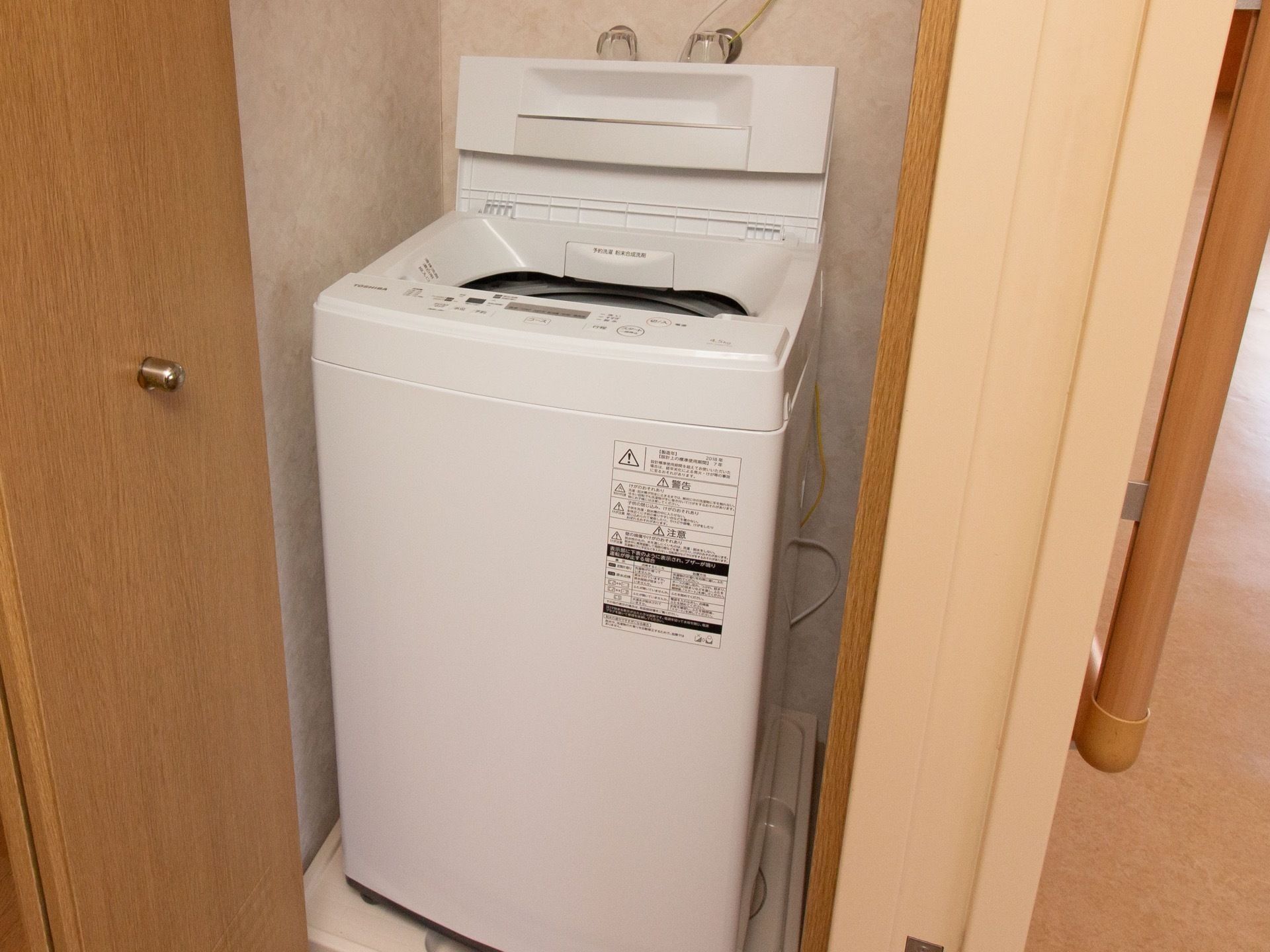 居室内には全自動の洗濯機が置かれている。すっぽりと壁に収まっている。部屋にいながら気軽に洗濯を行うことができる。