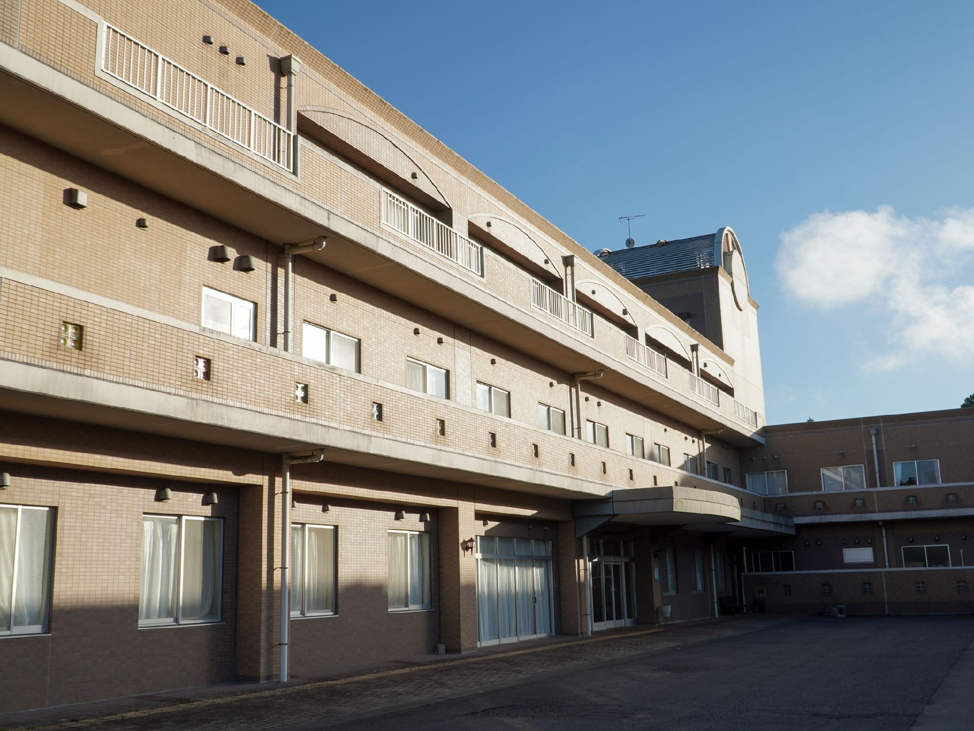 茶色の3階建ての建物ときれいな青空