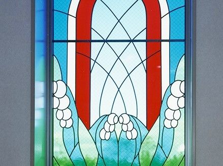 スズランの絵が描かれたステンドグラスがはめられた窓。窓の向こう側には緑が広がっている。