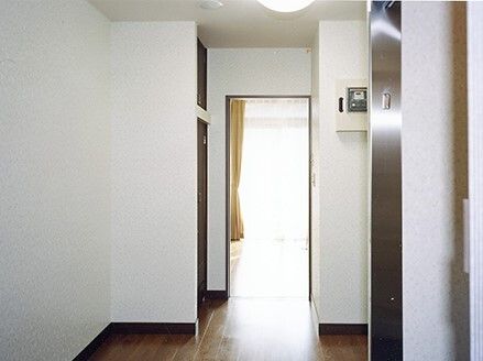 細長い廊下の奥にはフローリングの洋間があり、大きな窓にはカーテンが付いているのが見える。