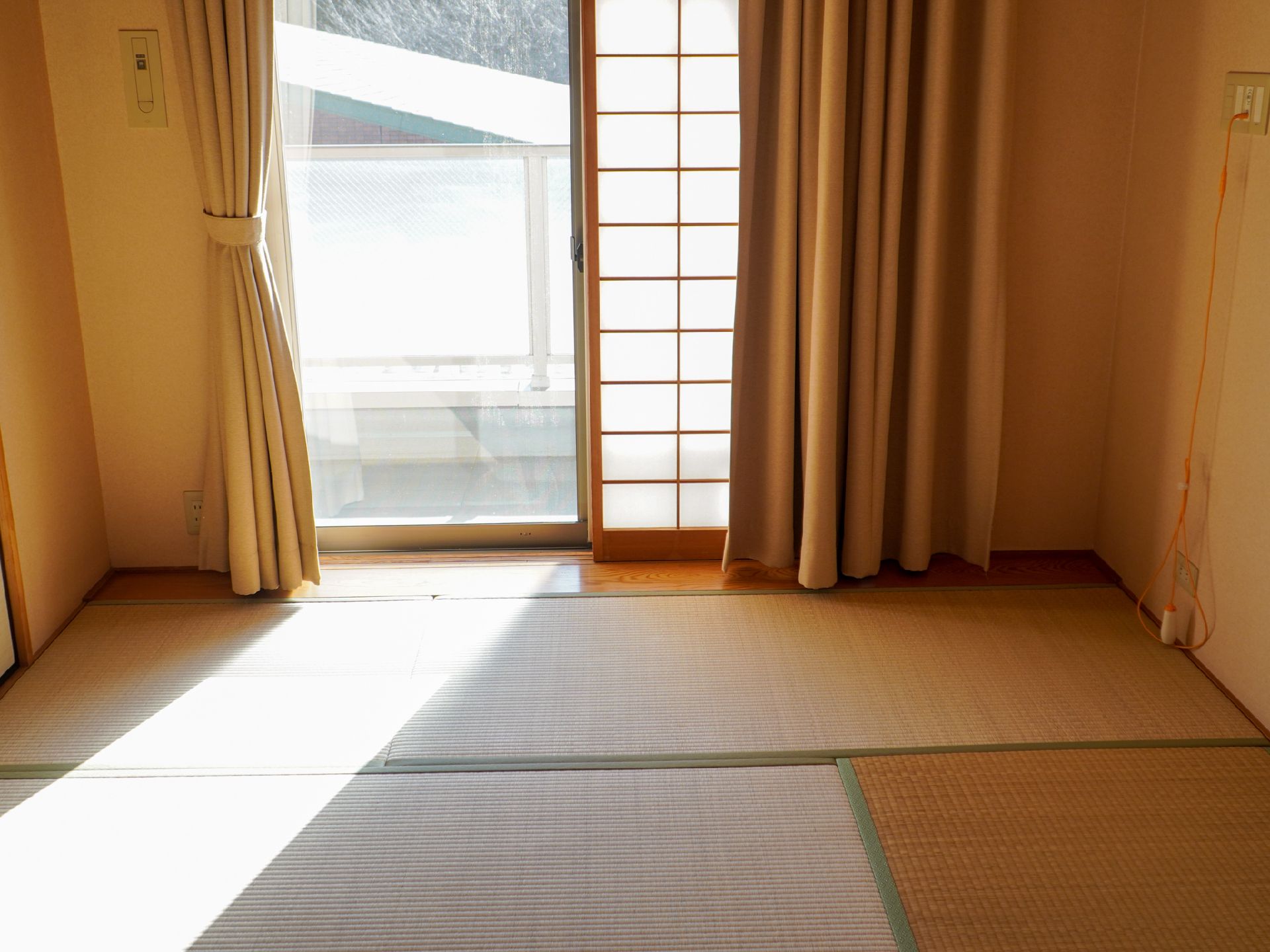 家具や家電の置かれていない広々としたフローリングの洋間が右にあり、左側には障子が付いた畳敷きの和室がある。