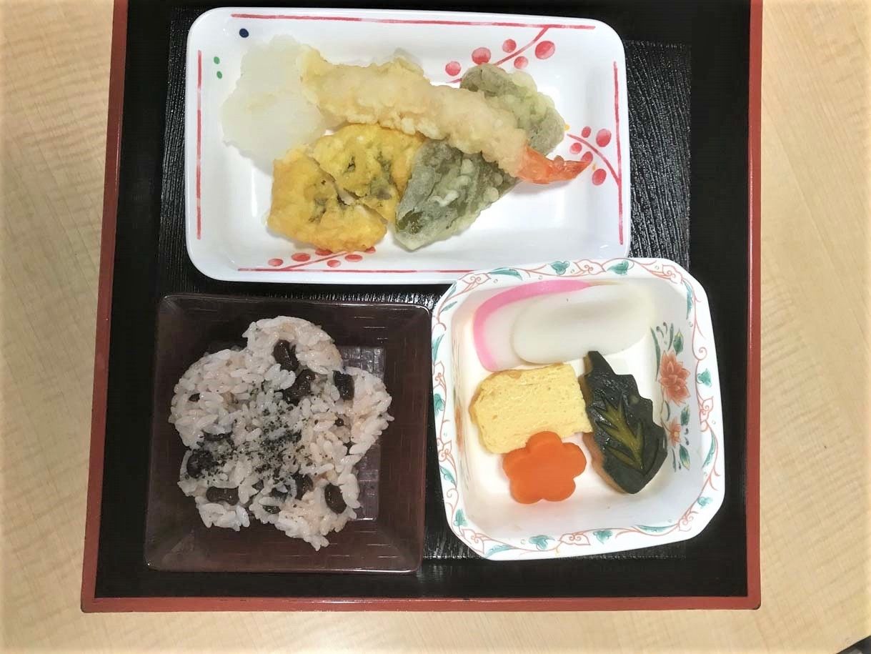 花形にくりぬかれたおこわと煮物、てんぷらが乗っている行事食のような食事メニュー
