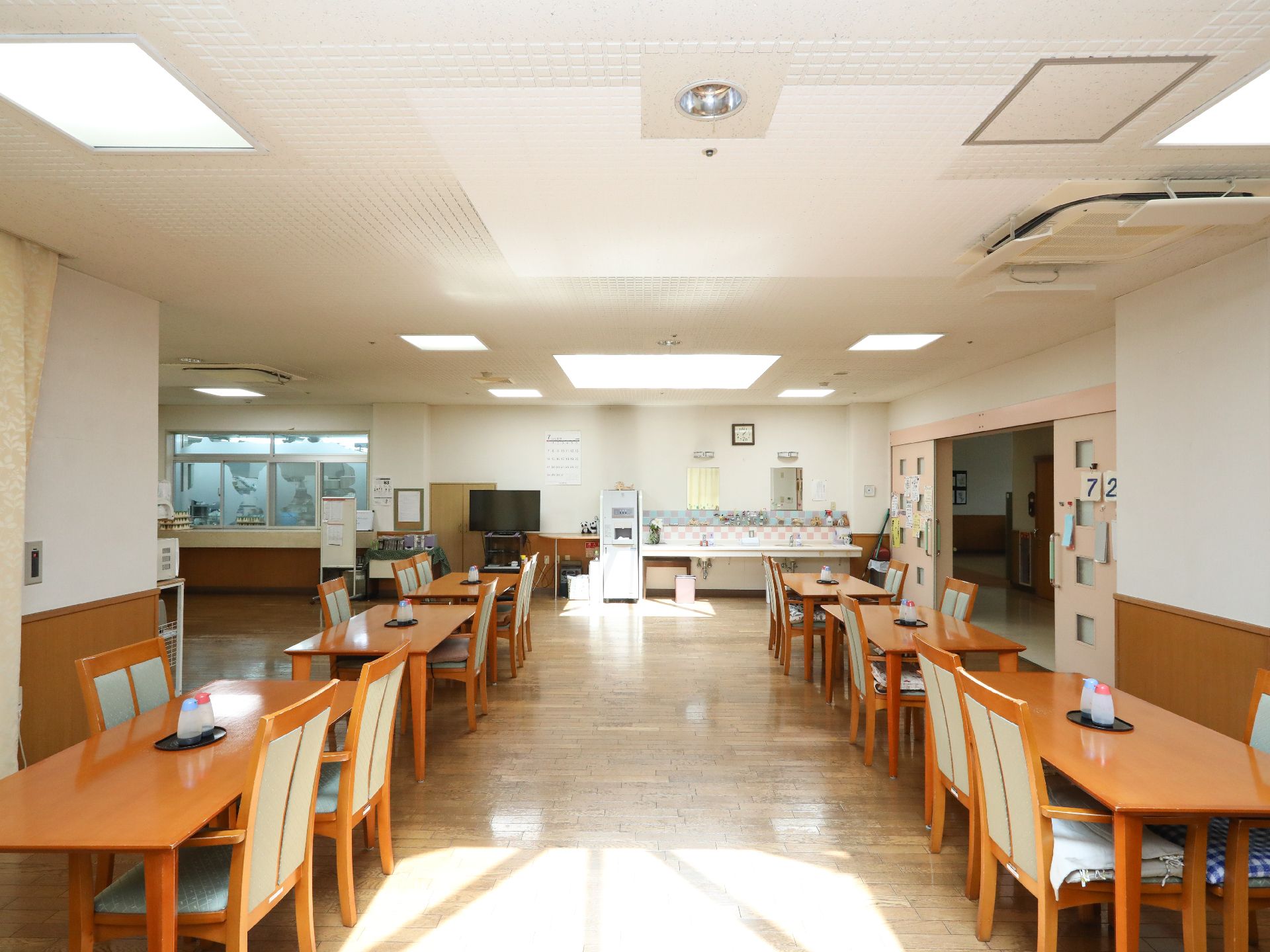入口近くに洗面台が設置されている、日当たりのよい食堂