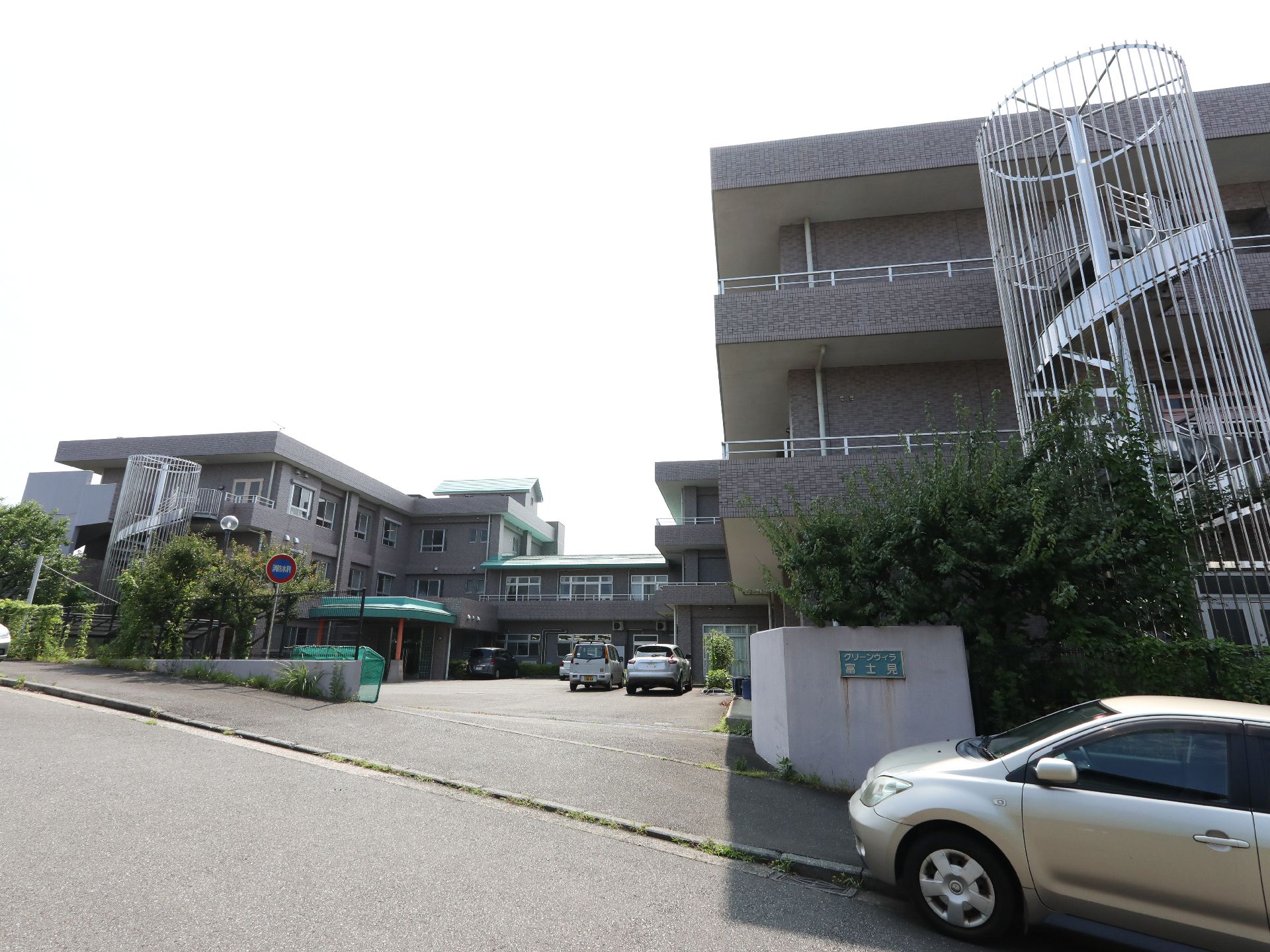 駐車場スペースが手前に広がる広い敷地とその奥にある建物の写真