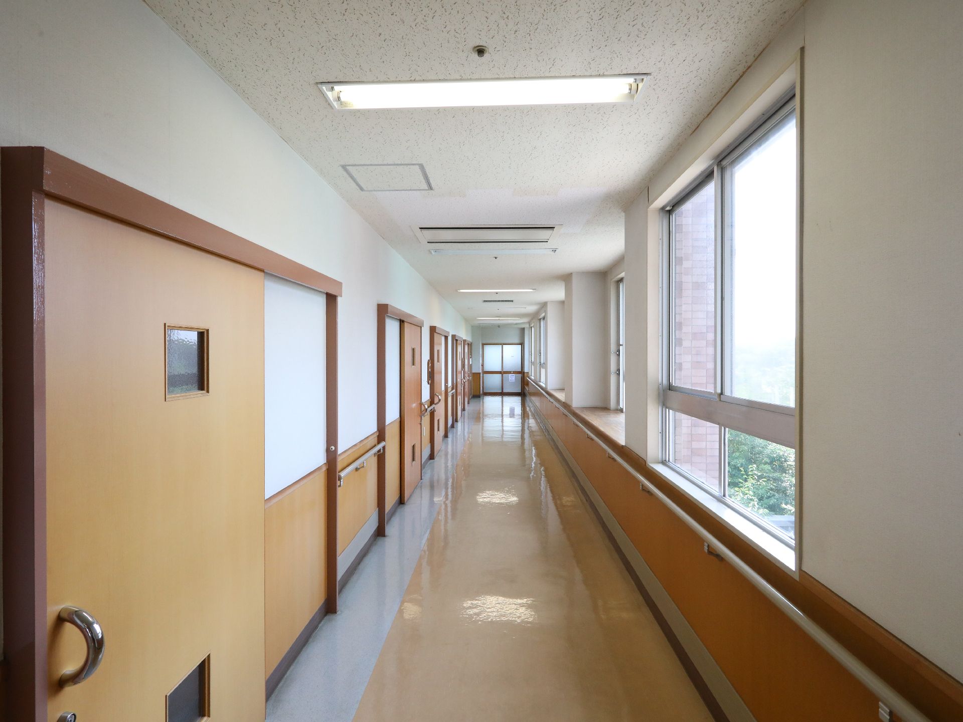 長く続く廊下の様子。オールバリアフリーの床と両側にある個室のドアが写っている