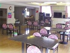 4人掛けのダイニングテーブルが複数並んだ食堂にはテレビやカラオケセットも置かれ、壁にはカレンダーなどが飾られている。