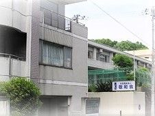 グレーの建物は重厚感がありベランダも付いている。周辺には緑も多い。