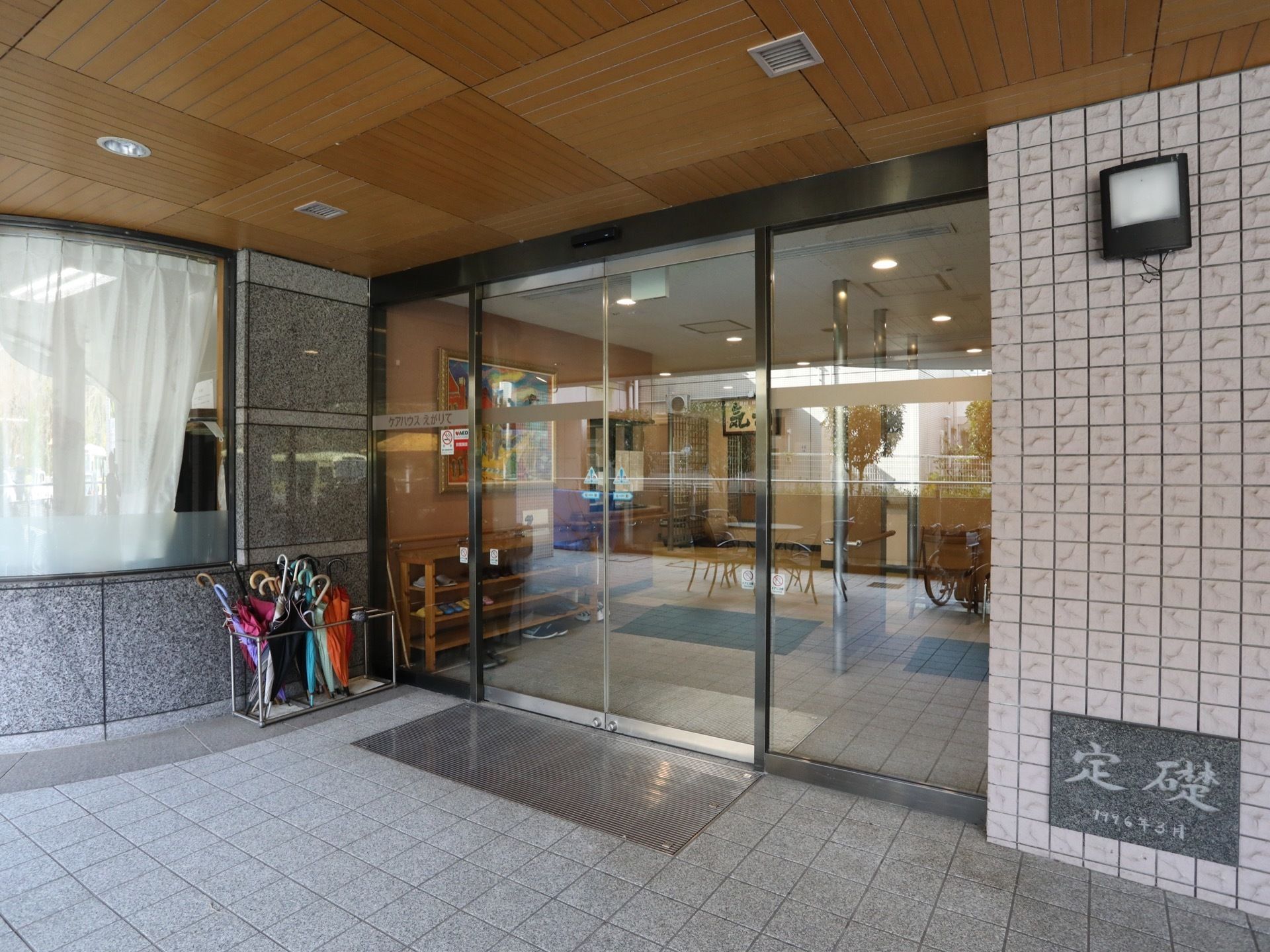 間口の広いガラス張りの自動ドアが設置されている玄関である。床はグレーを基調としたタイル張りとなっている。