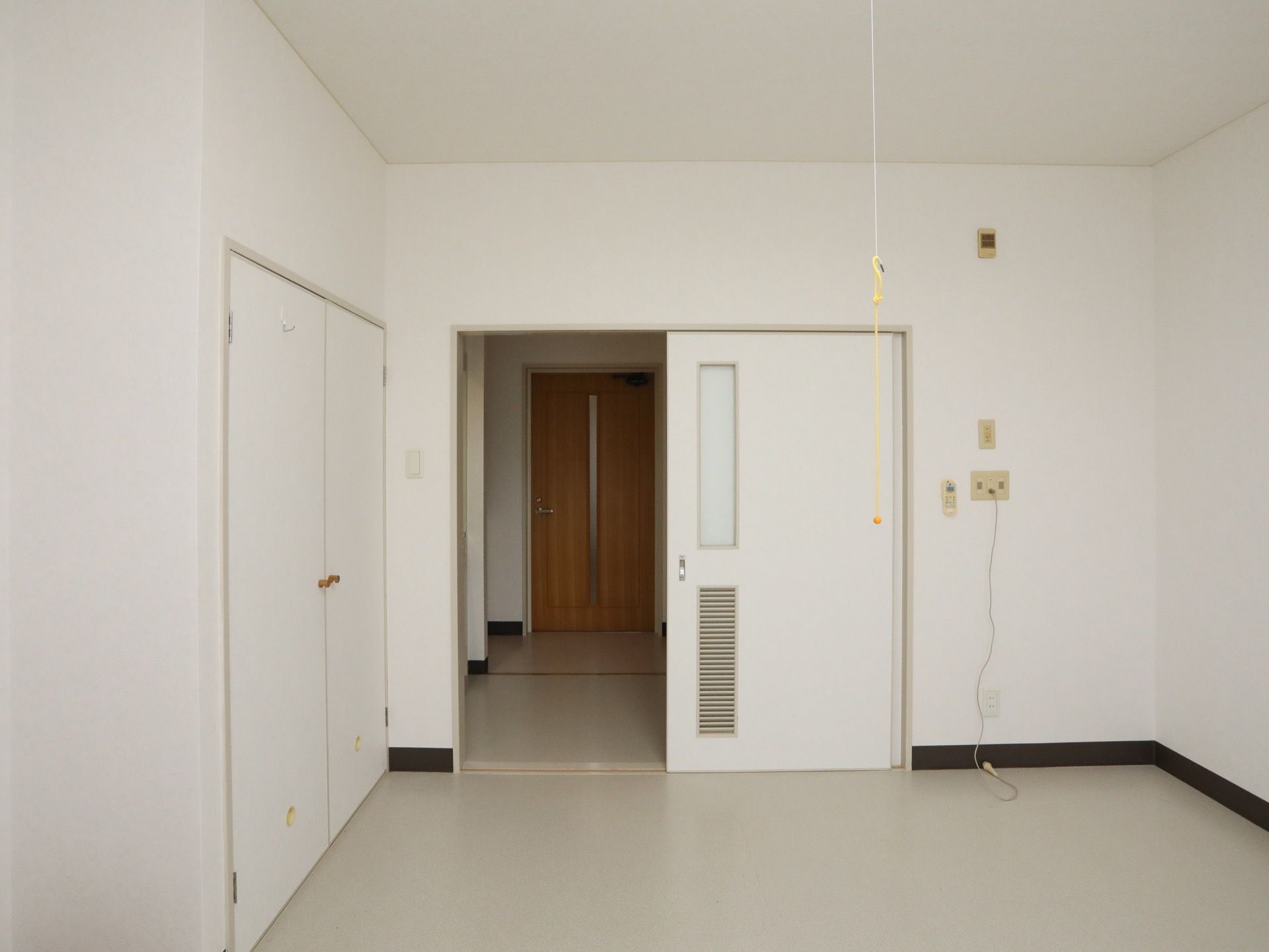 白を基調とした清潔感あふれる明るい居室。手前の部屋には収納スペースが確保されており、壁にはナースコールが設置されている。