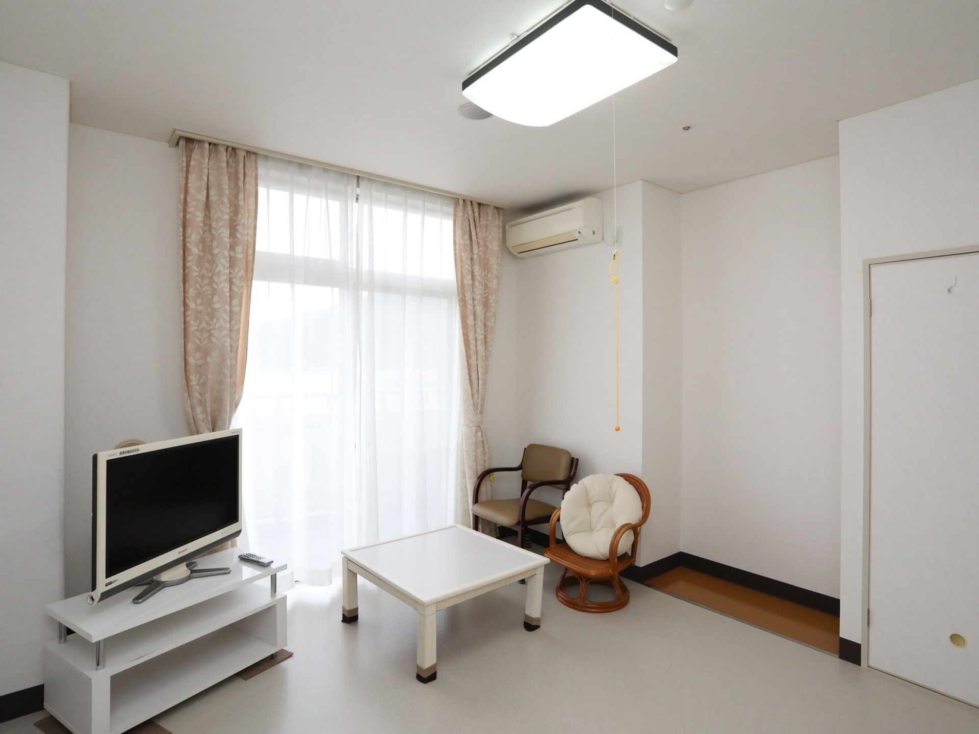 エアコンが完備されているワンルームの居室である。天井には照明が設置されており、紐が取り付けられている。