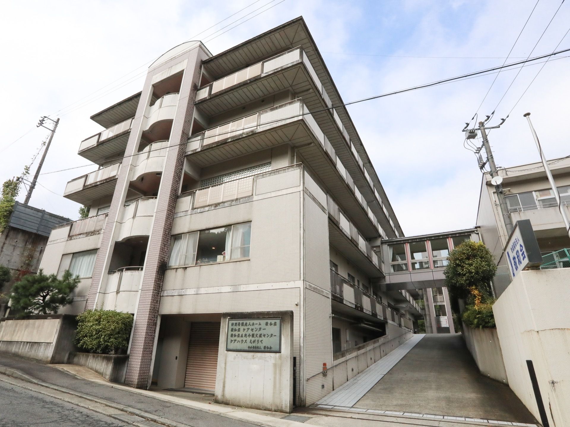 居宅介護支援センターや特別養護老人ホームが併設されている住まいである。道路沿いに、看板が設置されている。