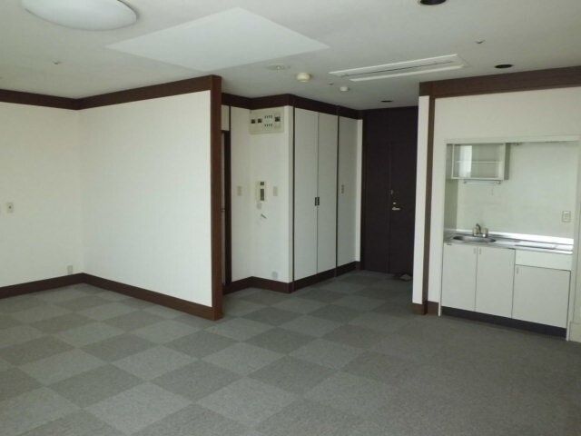 高齢者2名とスタッフが手を握りながら談笑している様子。施設内の会話の一画面