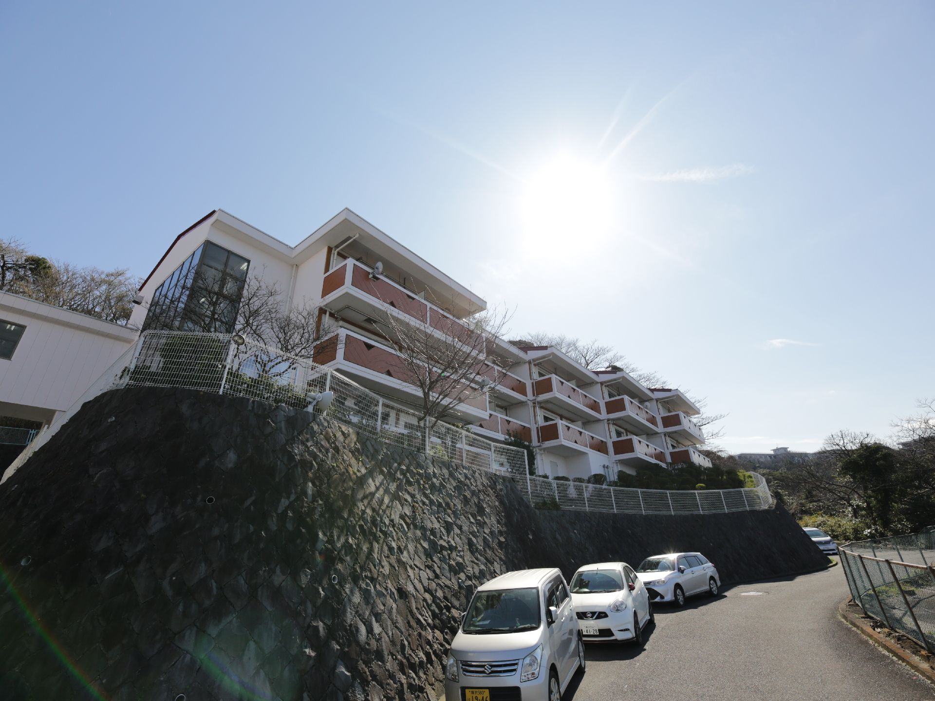 カーブした坂道の上にある敷地に建つ、階段状になっている施設外観