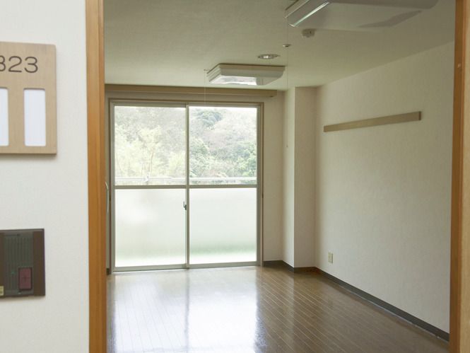 おおきな窓にカーテンはなく、照明やピクチャーレールが付いたフローリングの部屋。