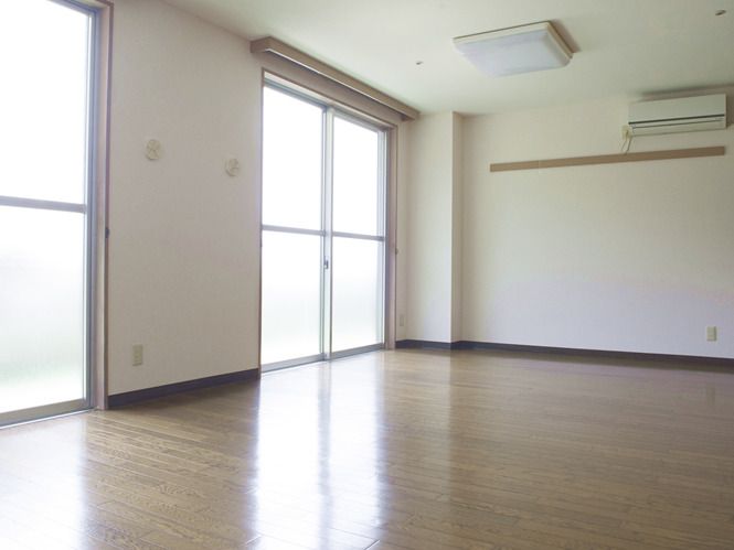 フローリングの広い部屋には家具はなく、壁にはエアコンが付いている。大きな窓が二つある。