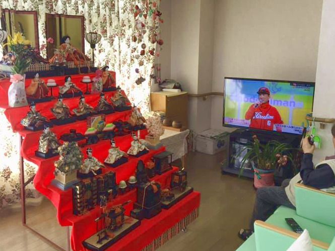 おおきなひな壇が飾られている館内。テレビが設置されていて、そばには入居者がいる。