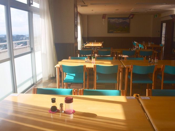グリーンの椅子がセットされた木製のテーブルが複数並んだ食堂には大きな窓が付いている。