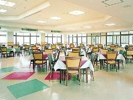 たくさんの窓が付いた食堂にはテーブルクロスがセットされたダイニングテーブルが複数置かれている。