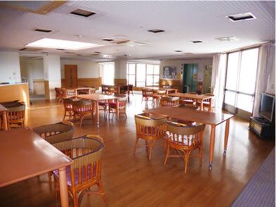 木製のダイニングテーブルが複数置かれた食堂にはテレビもあり、大きな窓がたくさん付いている。