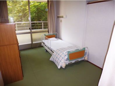 大きな窓が付いた居室には寝具付きのベッドやタンスが置かれている。窓の外には緑が広がり、日当たりも良好。