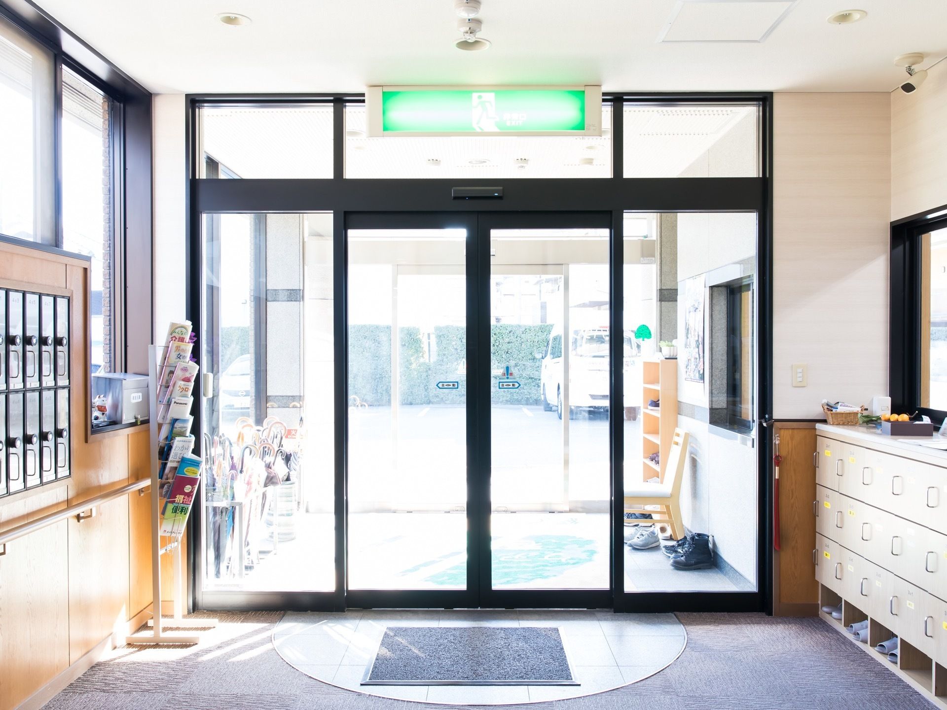 玄関の自動ドアは二重になっていて、傘立てや靴が見える。鍵付きの郵便受けがあり、入居者様のプライバシーにも配慮している。