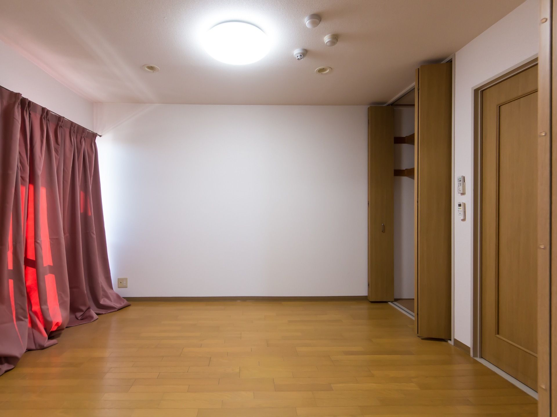 白い壁と木を使用した居室はナチュラルな雰囲気がある。床は明るい色のフローリングになっている。クローゼットや窓も大きい。