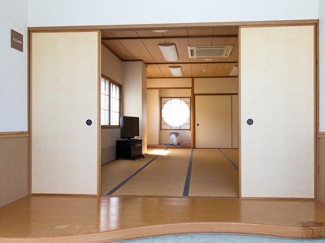 円形の窓には障子が設置され、畳が敷かれた広い部屋にはテレビが置かれ、部屋の名前が書かれている。