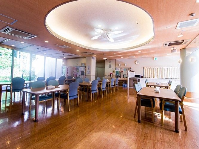 大きな窓が付いた食堂には青い椅子がセットされたダイニングテーブルが並び、大きな照明も付いている。