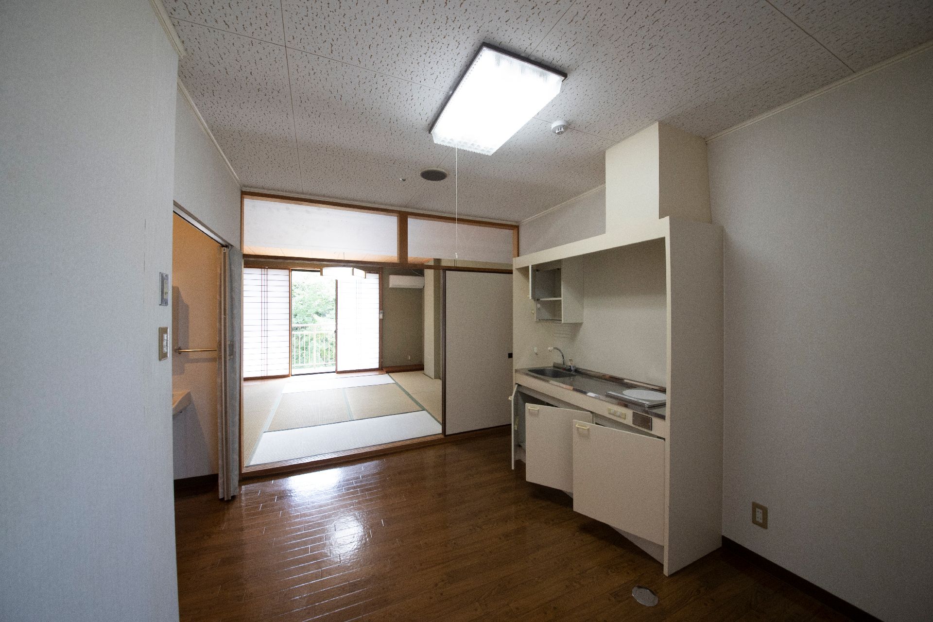 カーディガンを着た高齢女性が笑顔でエプロンを付けた女性スタッフに寄り添っている。