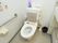 トイレのタンク前にはゆったりとご使用いただけるよう背もたれのクッションを設置している。壁には手すりと緊急用のボタンがある。