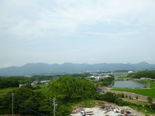 緑豊かな周辺環境。大きな池もあり、手前の広場のようなところにはトラックなどが止まっている。