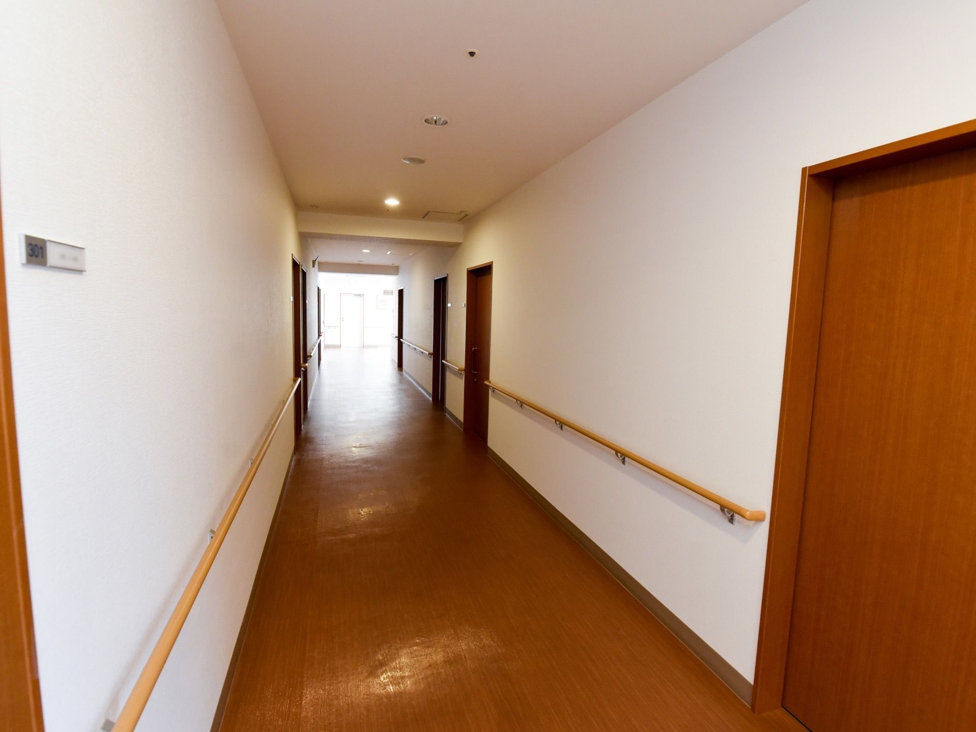 真っ白な壁とブラウンの木目調の床の色とのコントラストが美しい廊下である。照明がたくさんあるので明るい。エアコンが完備されている。