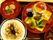 黒豆や田作りなどの正月料理が少しずつ並べられた皿やちらし寿司、吸い物、煮物が用意されている。