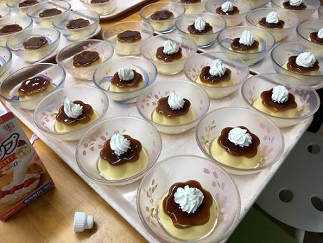 たくさんの器に盛り付けられた生クリームをトッピングしたプリン