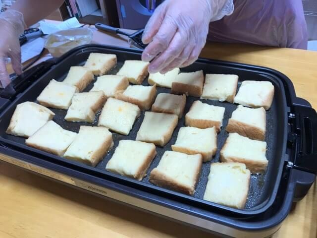 ホットプレートで卵と牛乳を染み込ませたたくさんのパンを焼く様子
