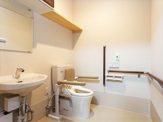 手すりや背もたれが付いたトイレは広く、手洗い場や収納スペース、呼び出しボタンなども付いている。