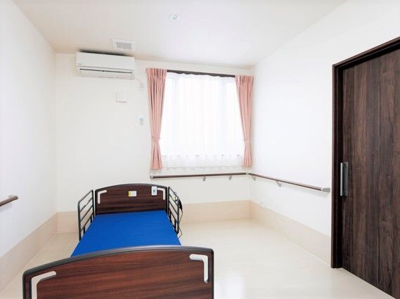 引き戸が付いた広い部屋には介護ベッドやカーテン付きの窓、エアコンなどが付き、大きな収納スペースも設置されている。