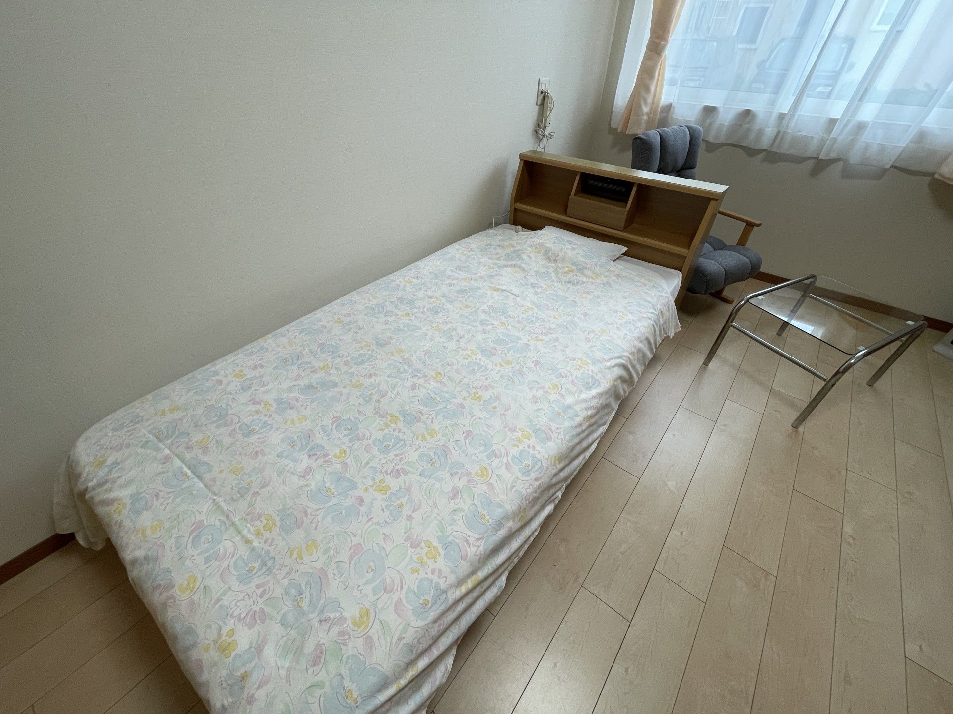 メガネをかけた高齢の男性がソファーに座りながら微笑みかけている様子。