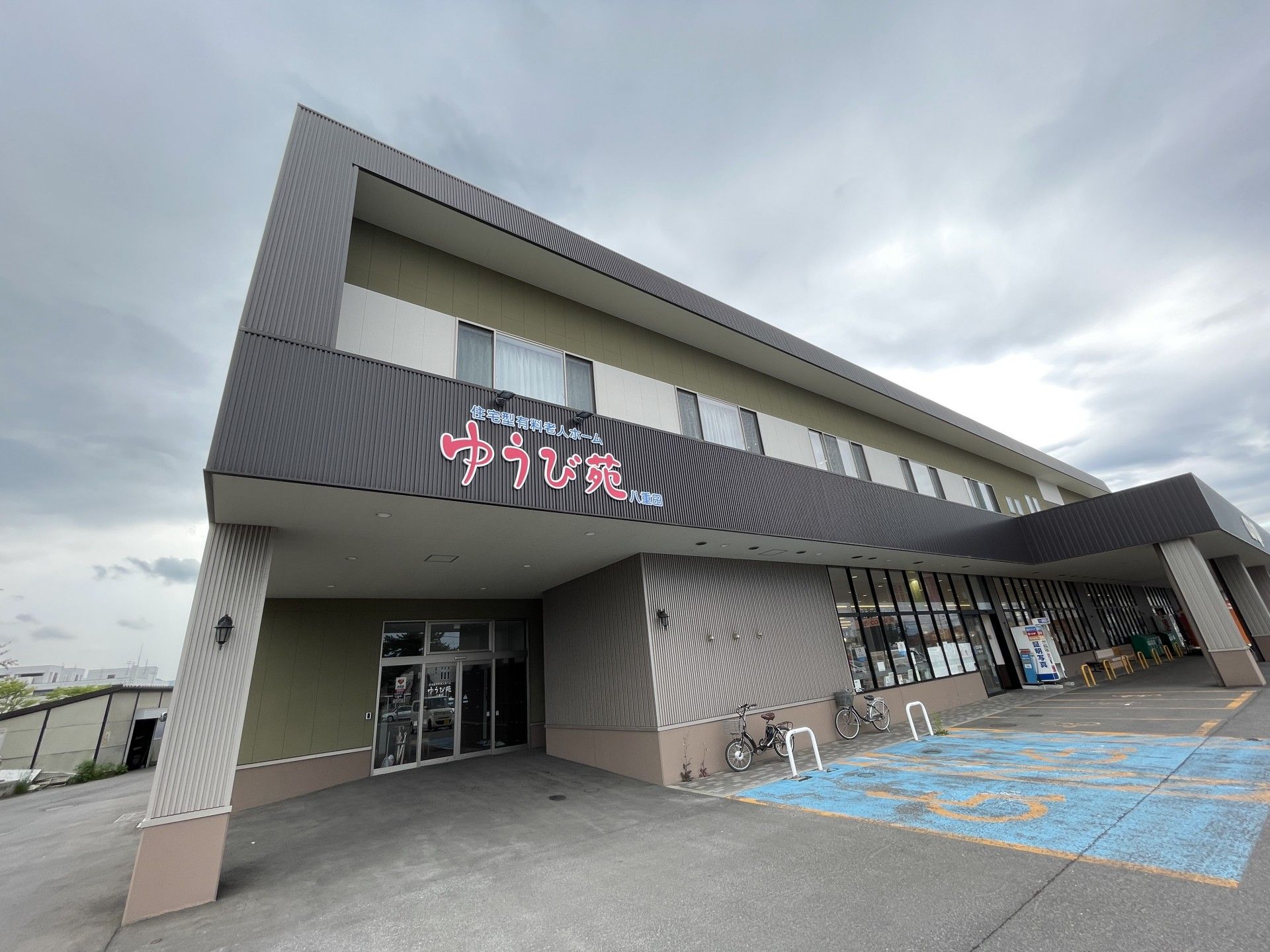 車椅子に乗った男性とその車椅子を押している女性が、自然の中で景色を眺めている。