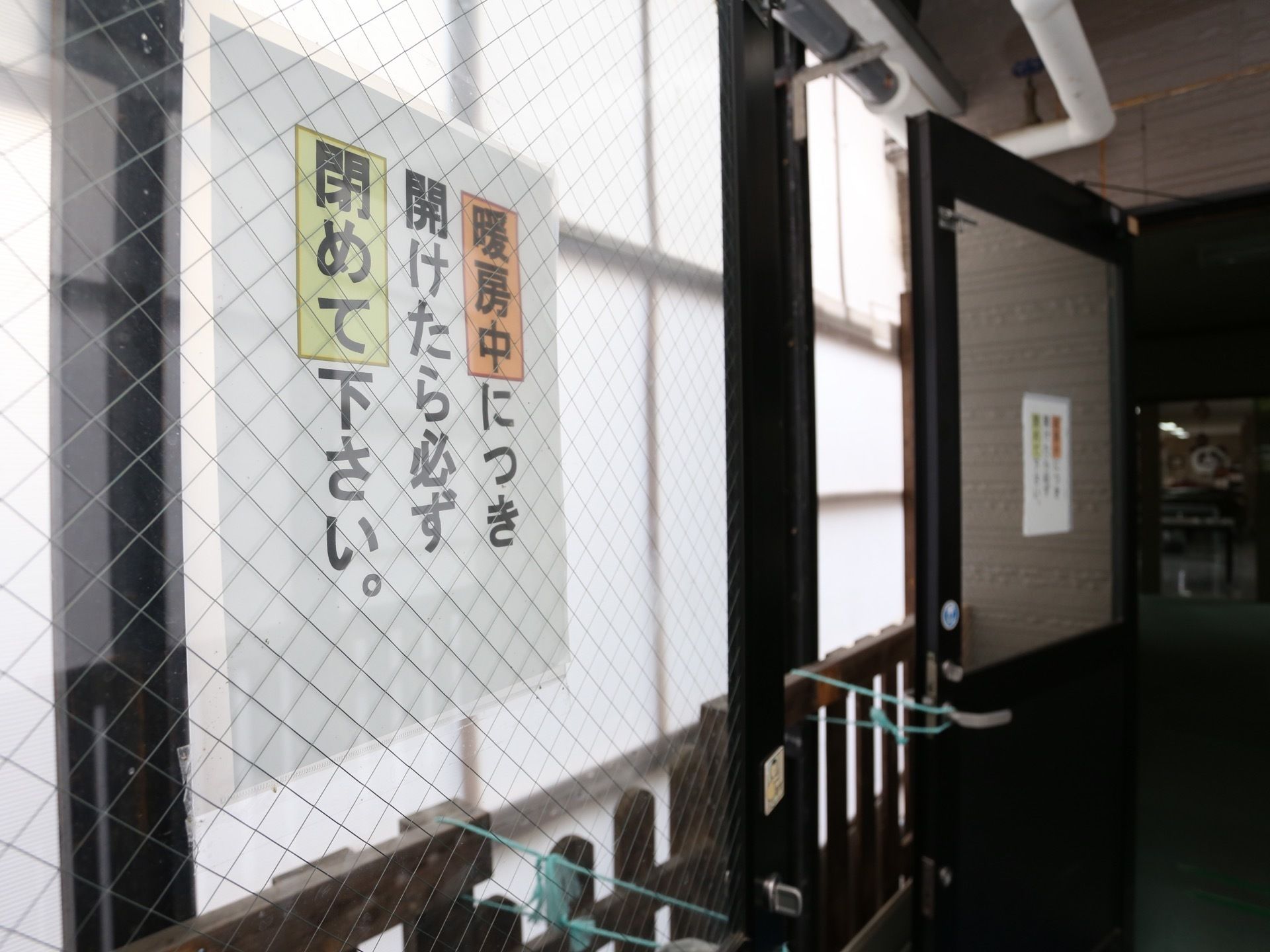 ドアが２つ開けられている共有スペースである。注意書きのプリントは、カラーになっていてわかりやすくなっている。
