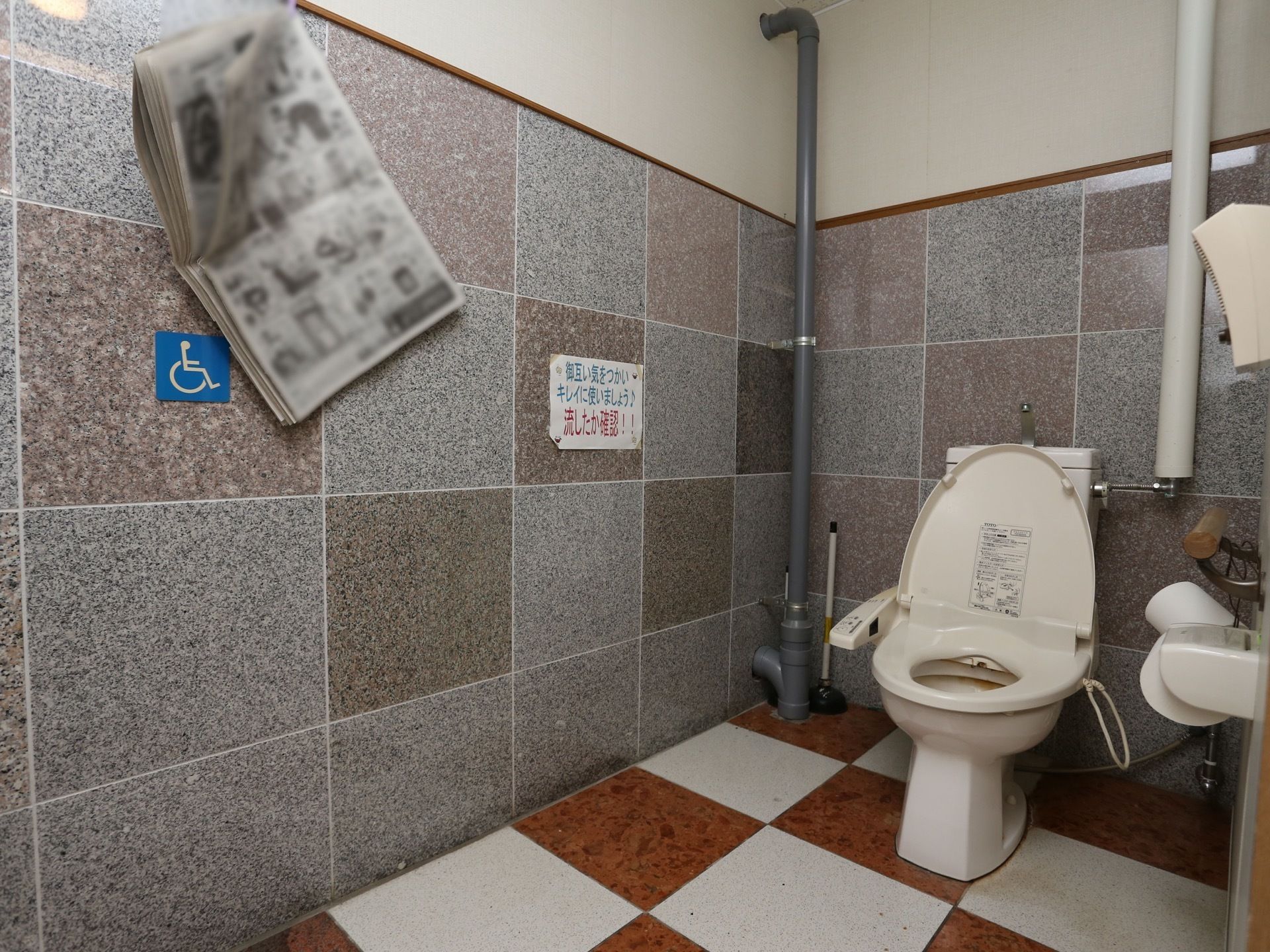 グレーのタイル調の壁になっている落ち着いた雰囲気のトイレである。温水洗浄便座を採用しているので、いつでも清潔に使用できる。