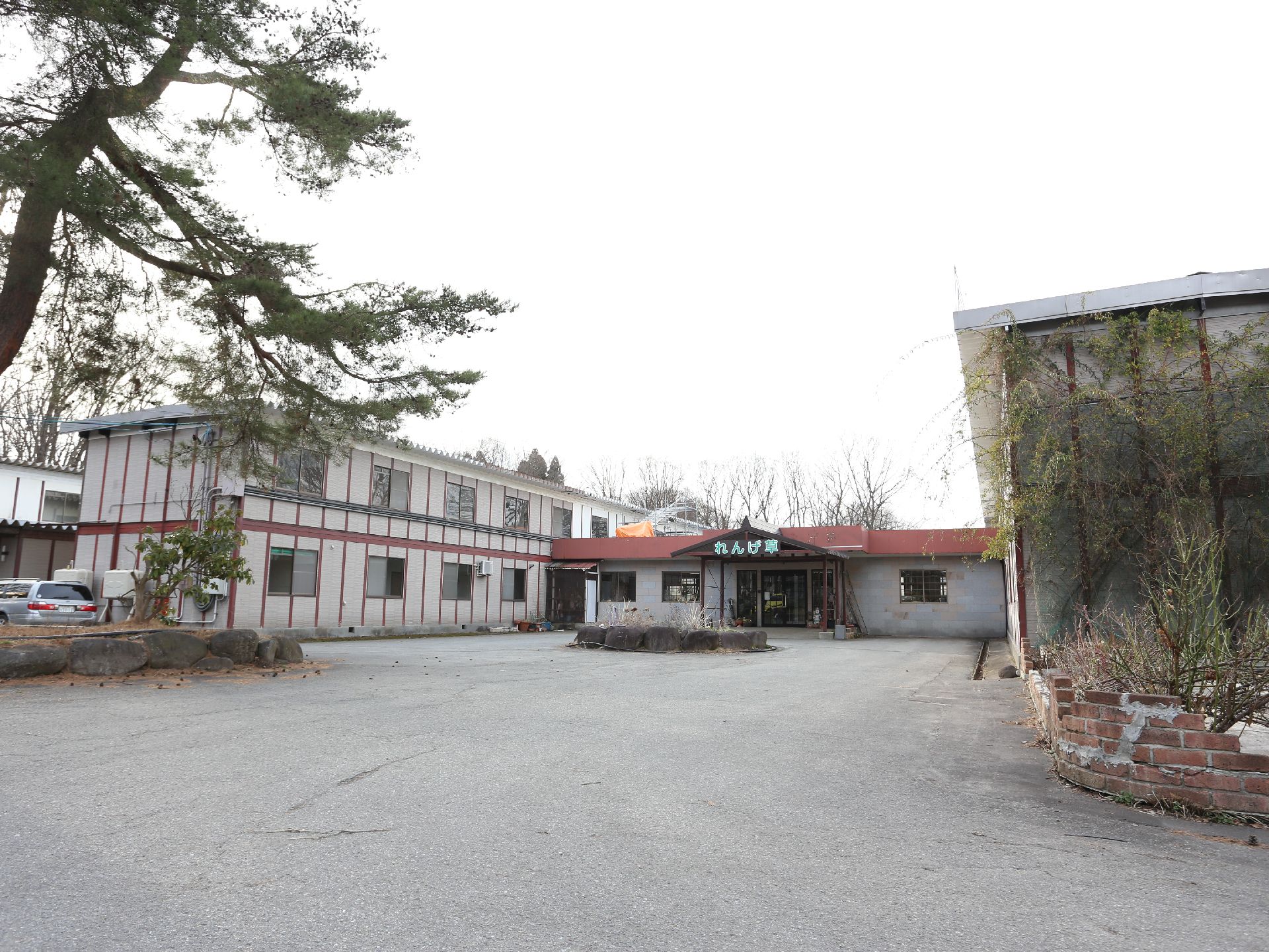 ２つの棟をつなぐ平屋建ての建物の中央部にある、施設名称が表示されている玄関