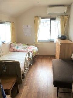 エアコンが設置されたフローリングの居室には窓が付き、カーテンも付いている。ベッドやタンスなどの家具もそろっている。