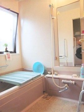 一人用の浴槽が設置された浴室。シャワーもあり、手すりが壁につき、大きな窓も設置されている。