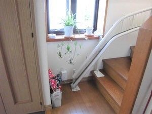 階段のそばにはスリッパラックが置かれ、窓が付き明るい。階段には階段昇降機のレールが付いている。