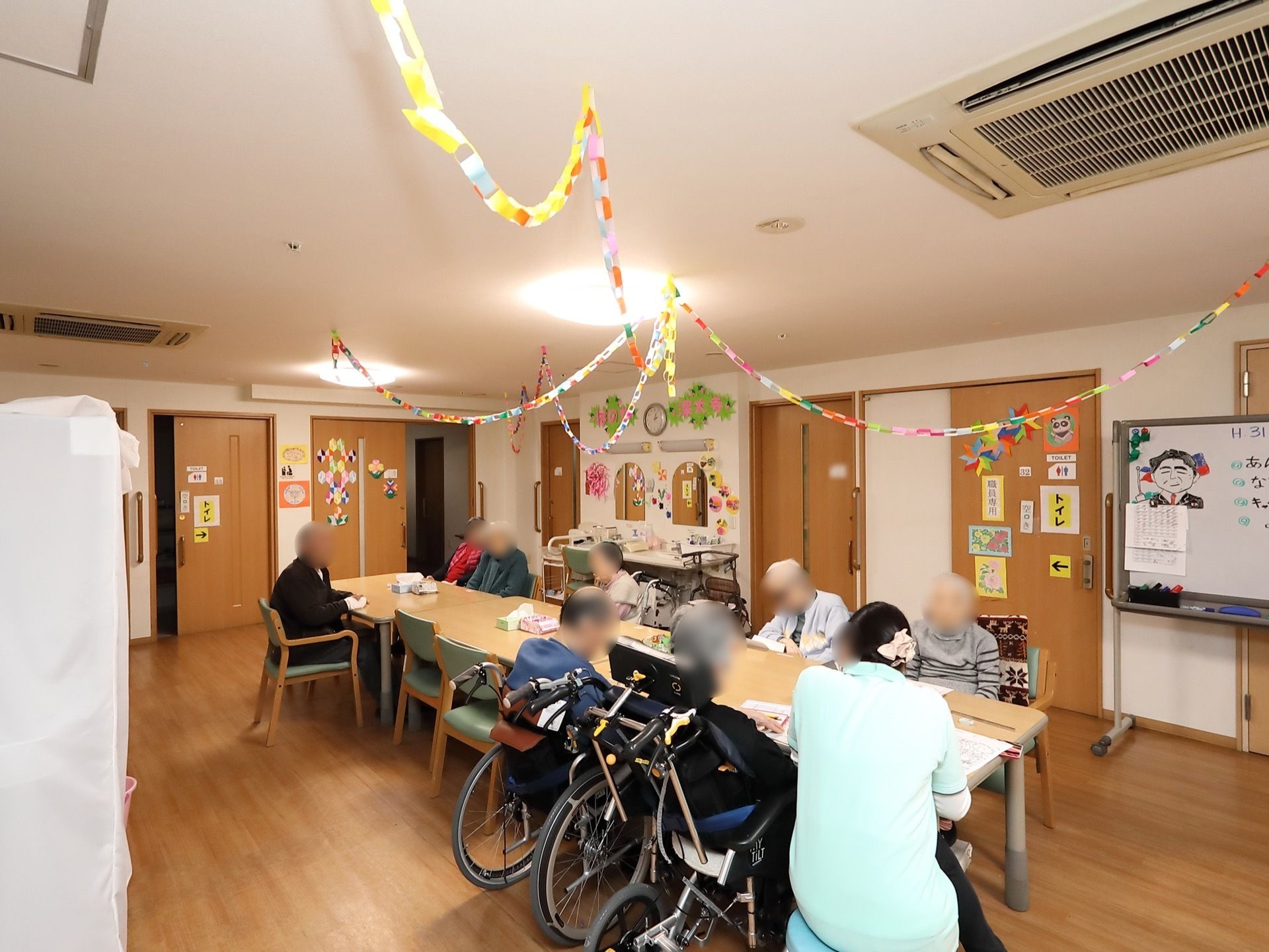 テーブルを並べて細長い席をつくっている。入居者様が一箇所に集まれるので、スタッフとともに会話を楽しみながら過ごせる。