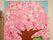 桜の木をちぎり絵で表現した作品である。花びらには多種多様な模様の紙が使われている。作品の上方には施設名が記されている。
