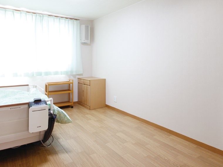 大きな窓があり明るい雰囲気。居室には、ベッドや収納家具もついている。